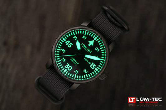 Close-up of Lum-Tec Combat B68 Day-Date with strong green lume on hands, markers, and day/date windows